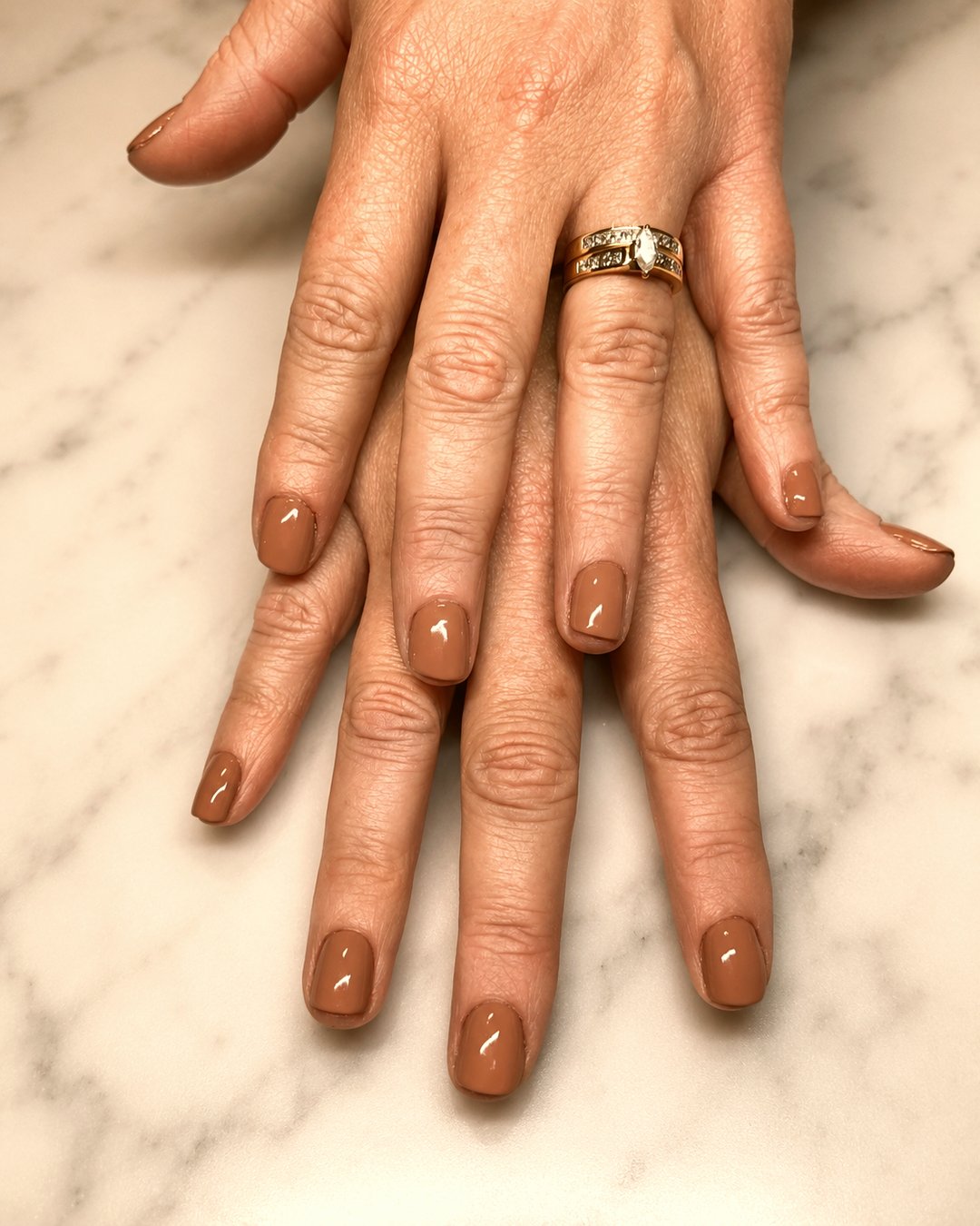 Freshly finished manicure in a warm neutral shade on marble