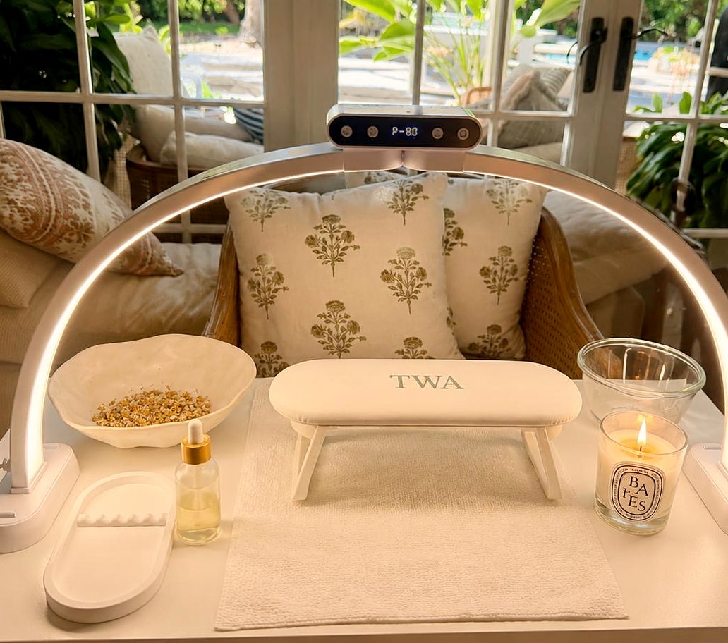 Professional lash and nail station with arc lamp and monogrammed armrest beside garden doors